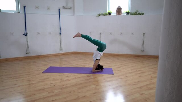 Woman performing Supported Headstand with Splits pose in room
