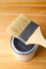 Paint brush on opened paint can isolated on wood plank	