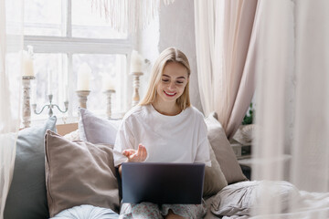 Young woman using modern laptop, talking at video call