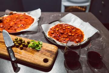homemade vegan pizzas getting prepared on kitchen benchtop with glasses of wine next to them, healthy plant-based food