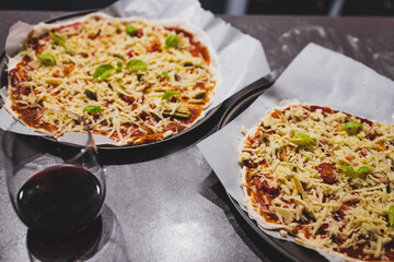 homemade vegan pizzas getting prepared on kitchen benchtop with glasses of wine next to them, healthy plant-based food