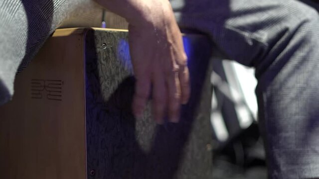 Plano detalle de una persona tocando un caj&oacute;n ac&uacute;stico en un escenario