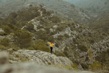 Woman with jacket in the distance on a mountain top with mist and raining in autumn