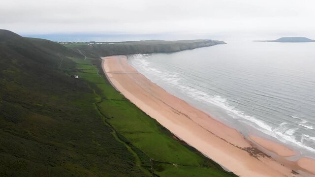 Forward Flying Drone Shot Over Rhossili Bay and Rhossili Beach, With Worms Head In The Background, in The Gower Peninsula, Llangennith, Wales
