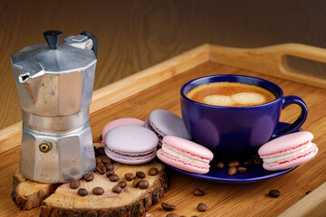 Cup of coffee, macaroons, and coffee beans on a platter and geyser coffee maker on a wooden tray.