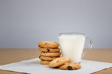 Cup of milk and cookies with raisins on a wooden table