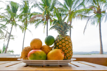 A plate of exotic fruits and palm trees on the background