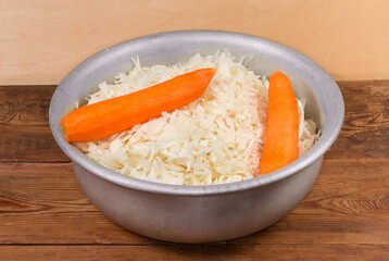Shredded white cabbage and whole carrots in large mixing bowl