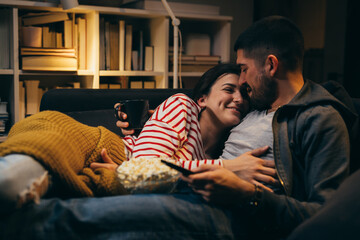 Fototapeta premium couple relaxing on sofa at home, watching television. evening scene