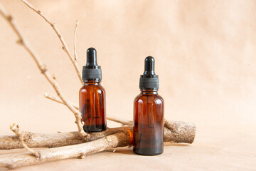 Cometic amber glass bottles and dry wooden driftwood on a pastel background. Skin care products...