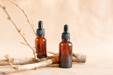 Cometic amber glass bottles and dry wooden driftwood on a pastel background. Skin care products packaging design. Spa concept.