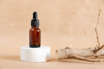 Cometic amber glass bottles and dry wooden driftwood on a pastel background. Skin care products packaging design. Spa concept.