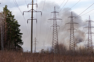 Overhead power lines against sky covered with smoke from fire