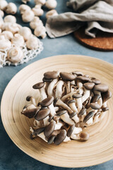 Fresh oyster mushrooms in wooden plate on the kitchen table.