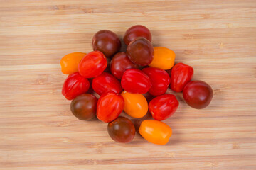 Top view of multicolored cherry tomatoes on wooden cutting board