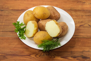 Potatoes boiled in their skins on dish on rustic table