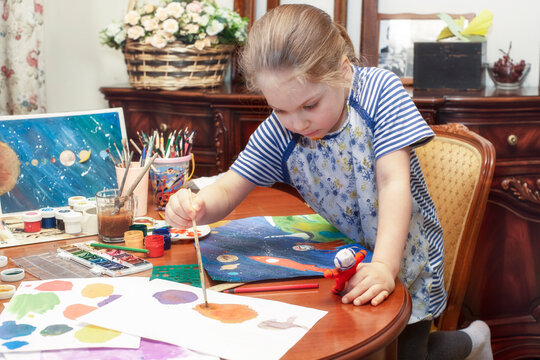 Preschool girl paints and makes papier mache crafts
