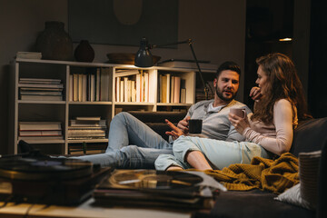 couple relaxing on weekend together at home listening to a music on record player