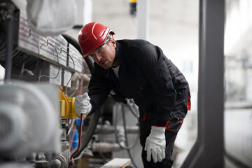 Portrait of worker in factory. Young man with helmet working in factory..