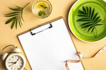 Composition with plate, alarm clock and measuring tape on a colored background. Diet concept and weight loss plan