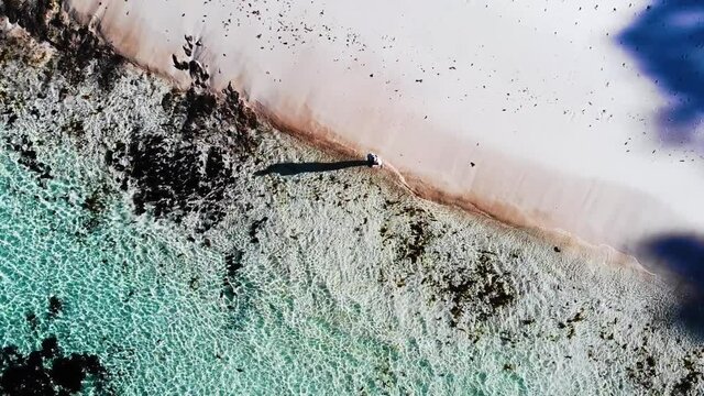 Slow Backwards Flying Drone Shot Of Hyams Beach, Showing The Turqouise Ocean And Waves Crashing Onto The White Sandy Beach