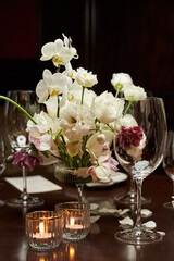 a transparent wine glass, a small white bouquet and two burning candles in candlesticks