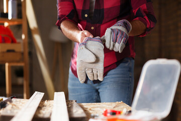 Close up of craftsman putting on protective gloves.