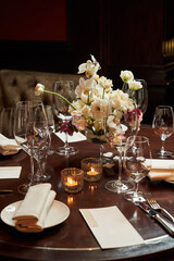 a table set for the holiday with a white bouquet in the center and burning candles