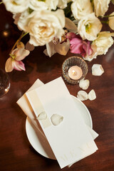 beautiful menu on a plate, burning candle and flowers top view