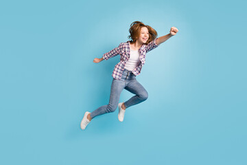 Fototapeta na wymiar Full length profile portrait of carefree kid raise fist flying look empty space isolated on blue color background