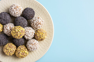 Healthy energy balls of dried fruits and nuts lie on a large plate on a blue background, horizontal orientation, flat lay, copy space, close-up
