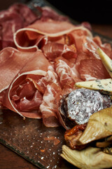 the meats are thinly sliced and arranged beautifully on the plate. jamon, ham and hard dry-cured sausage