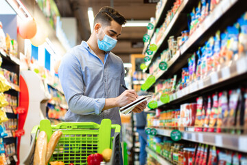 Arabic Man Taking Notes In Groceries Shopping List In Supermarket - obrazy, fototapety, plakaty