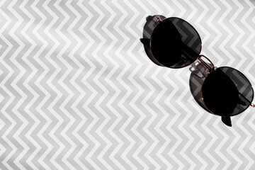 Round sunglasses on a light gray geometric background. Space for the text.