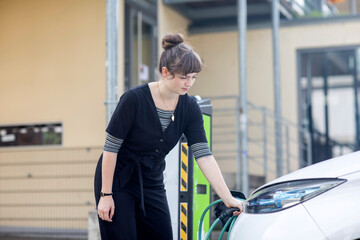 Junge Frau bei einer Elektroauto charger, Freiburg, BW, Germany