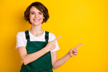 Portrait of pretty cheerful person beaming smile indicate fingers empty space isolated on yellow...