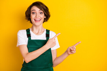 Photo of impressed cheerful girl direct fingers empty space unbelievable offer isolated on yellow color background