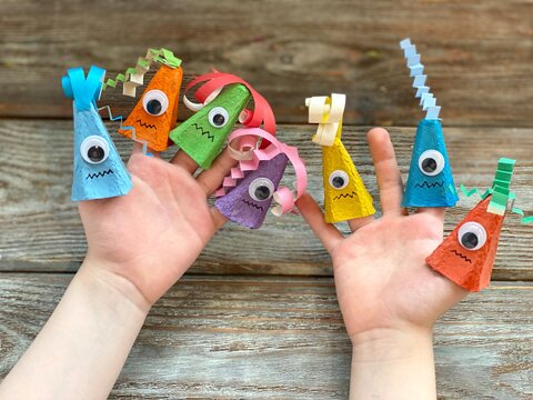 Cute monsters on children's hand, kids DIY from recycling egg box.