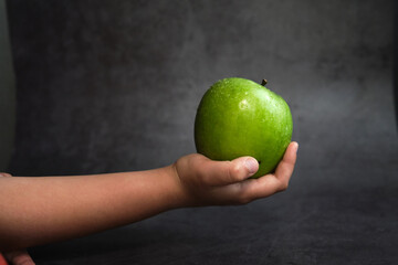 the girl holds a green apple in her hand
