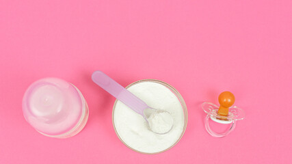 Powdered Milk, Baby Formula with spoon. Infant formula in bowl and bottle for feeding baby on pink background. Top view with copy space. Pastel color