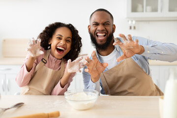 Black man and his daughter posing and playing in kitchen