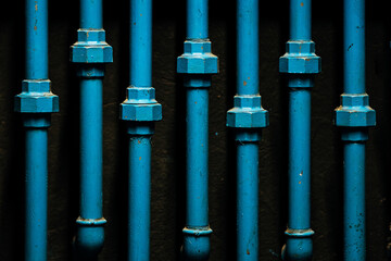 close up of parallel blue tubes on black wall