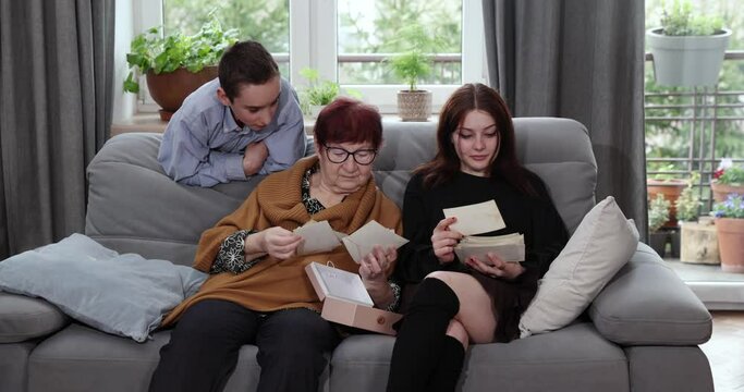 Granny showing photo album pictures to grandchildren , family history. Grandmother and granddaughters are looking at photos