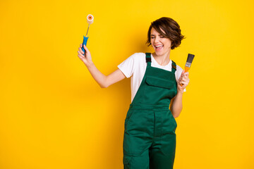 Photo of optimistic nice brown hair lady hold roller brush wear uniform isolated on yellow...