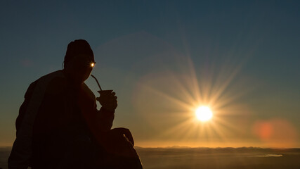 Gaúcho tomando chimarrão ao pôr do Sol