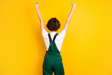 Back view photo of excited woman builder constructor raise fists in victory complete work isolated...