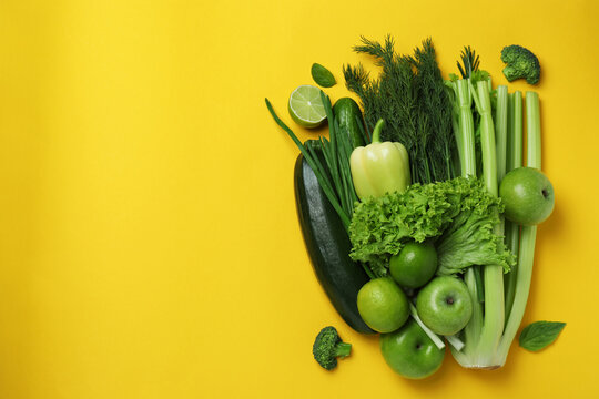 Fresh green vegetables on yellow background, space for text