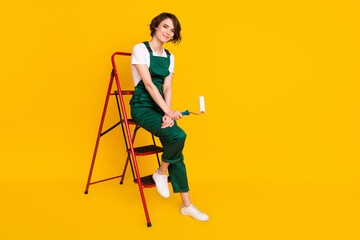 Full size photo of happy positive lovely woman painter sit ladder renovation home isolated on yellow color background © deagreez
