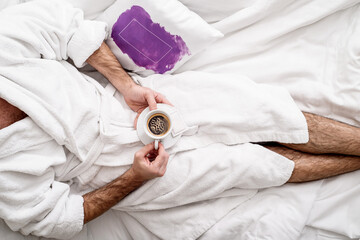 Coffee in bed. Man in a white coat is drinking espresso in bed. Top view. Flat lay. Breakfast at...