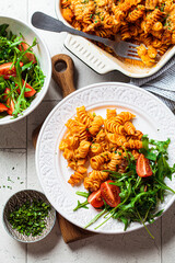 Baked pasta with chicken and cheese on white plate, gray background. Italian cuisine concept.